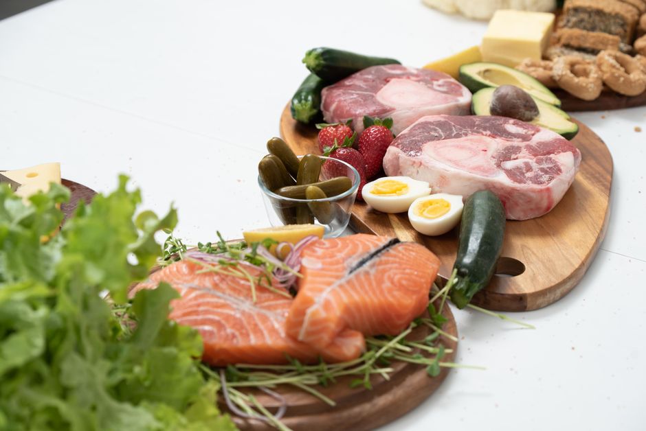 Alimentos ricos em ferro dispostos sobre mesa: carne vermelha, peixe, feijão, espinafre e ovos