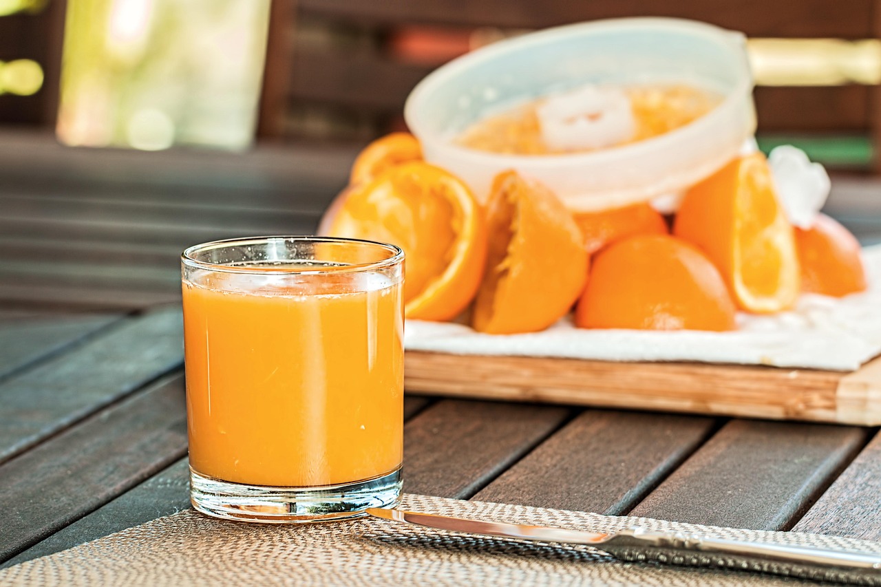 Suco natural de laranja fresco em copo transparente ao lado de laranjas inteiras