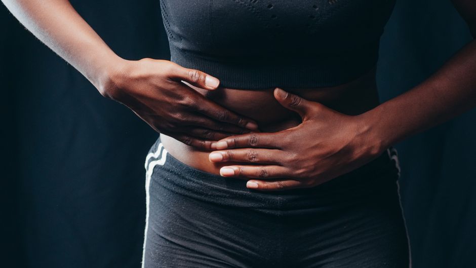 Mulher segurando a barriga com expressão de desconforto
