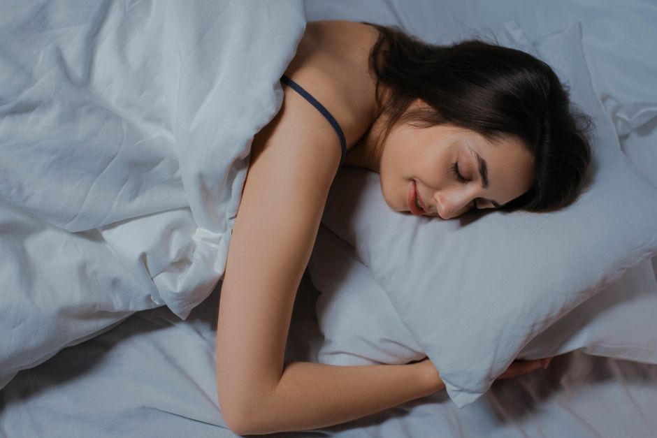 Mulher dormindo profundamente em quarto escuro, mostrando importância do sono para memória