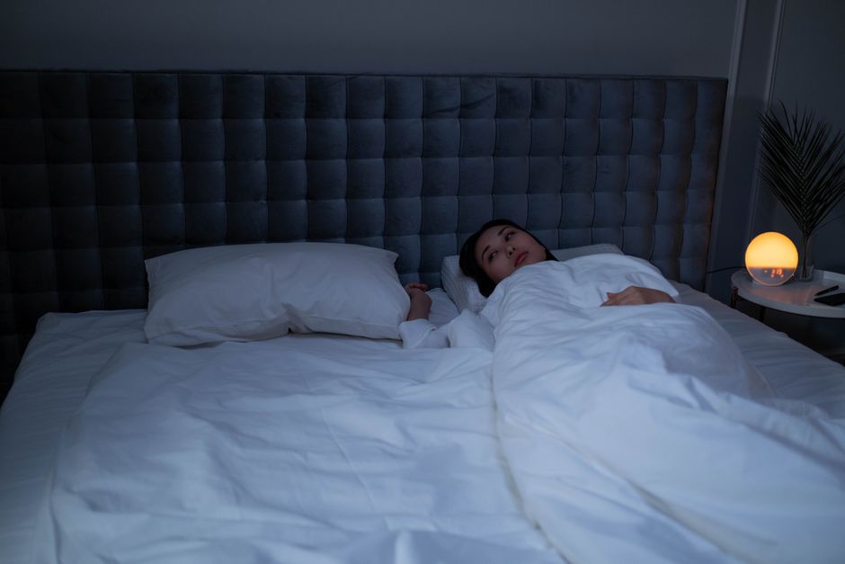 Mulher acordada na cama durante a noite, dificuldade para dormir