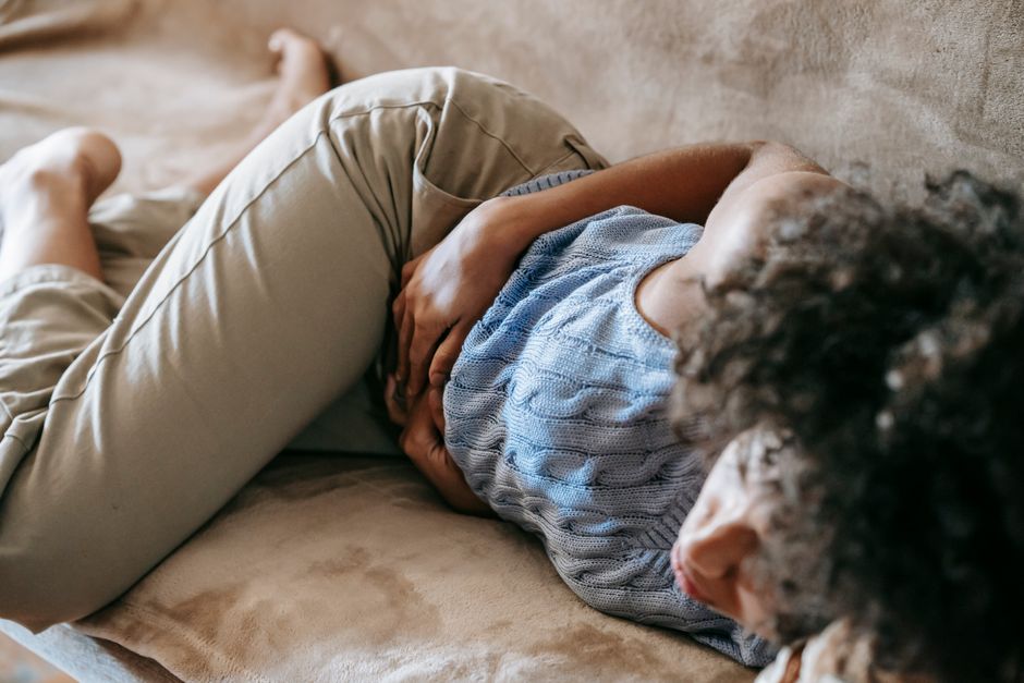 Mulher descansando no sofá com expressão de mal-estar e náusea