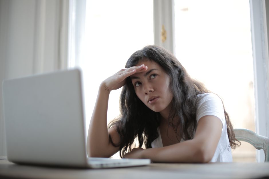 Mulher na mesa de trabalho com expressão de dificuldade e cansaço mental
