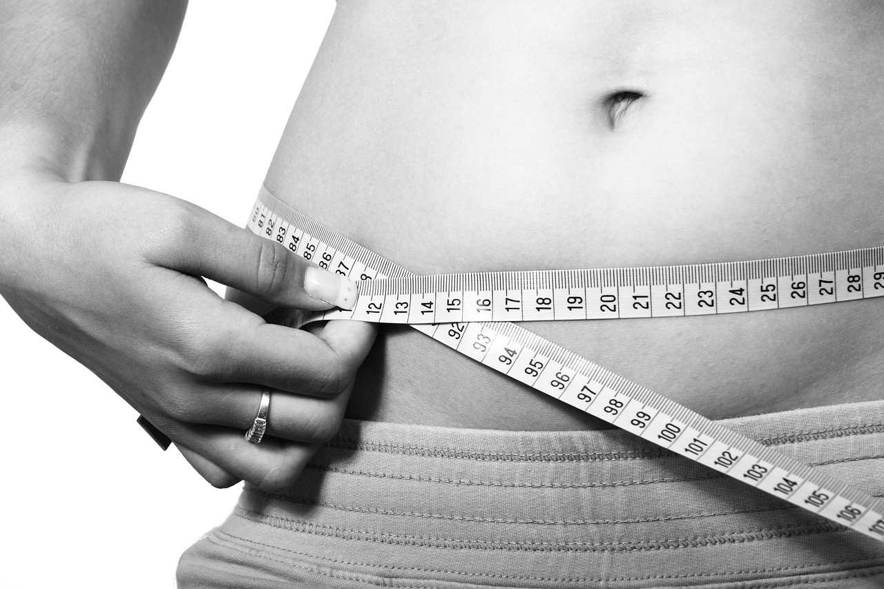Mulher medindo circunferência abdominal com fita métrica