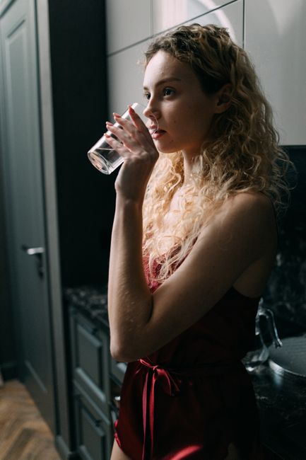 Mulher bebendo um copo de água na cozinha