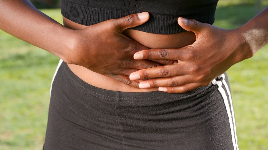 Pessoa apoiando as mãos na barriga com desconforto abdominal
