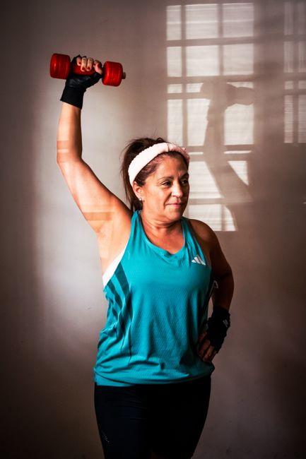 Mulher mais velha faz exercício de força com um halter em casa