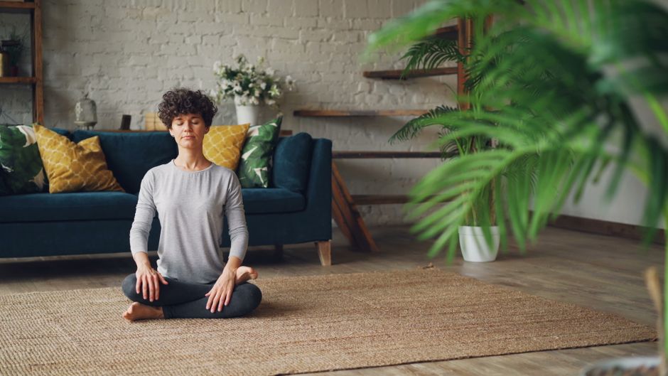 Mulher em posição de meditação praticando respiração profunda para relaxamento