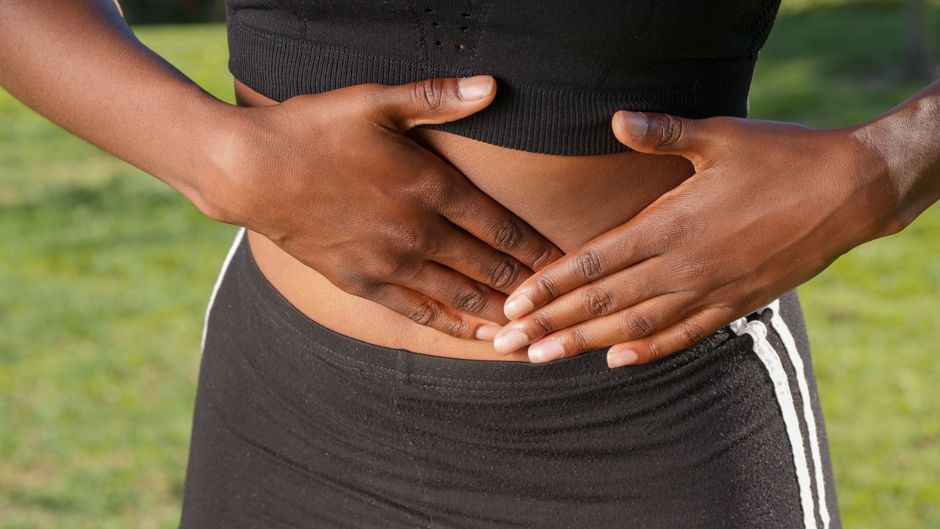 Mulher com as mãos na barriga sentindo desconforto abdominal