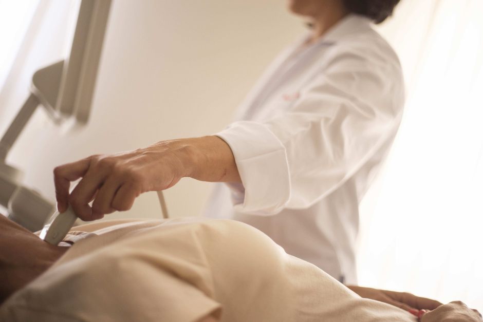 Médico realizando ultrassom com Doppler nas veias da perna